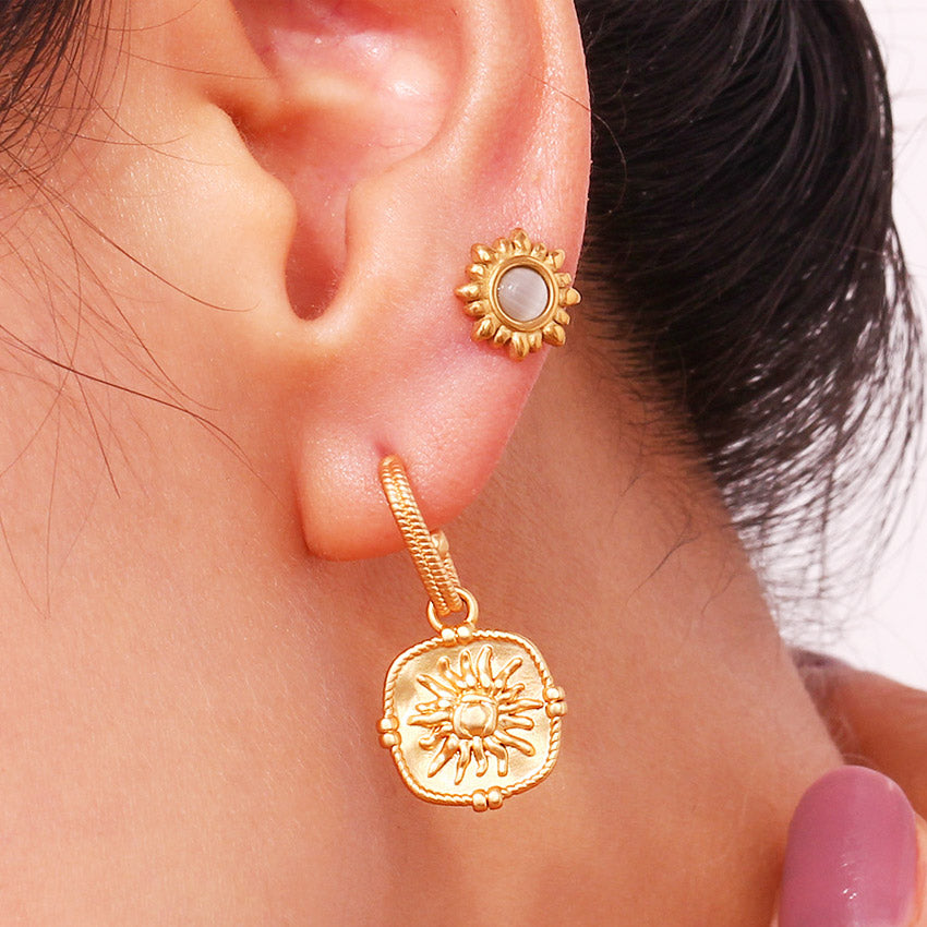 Detailed view of the sun motif on the gold PVD earrings