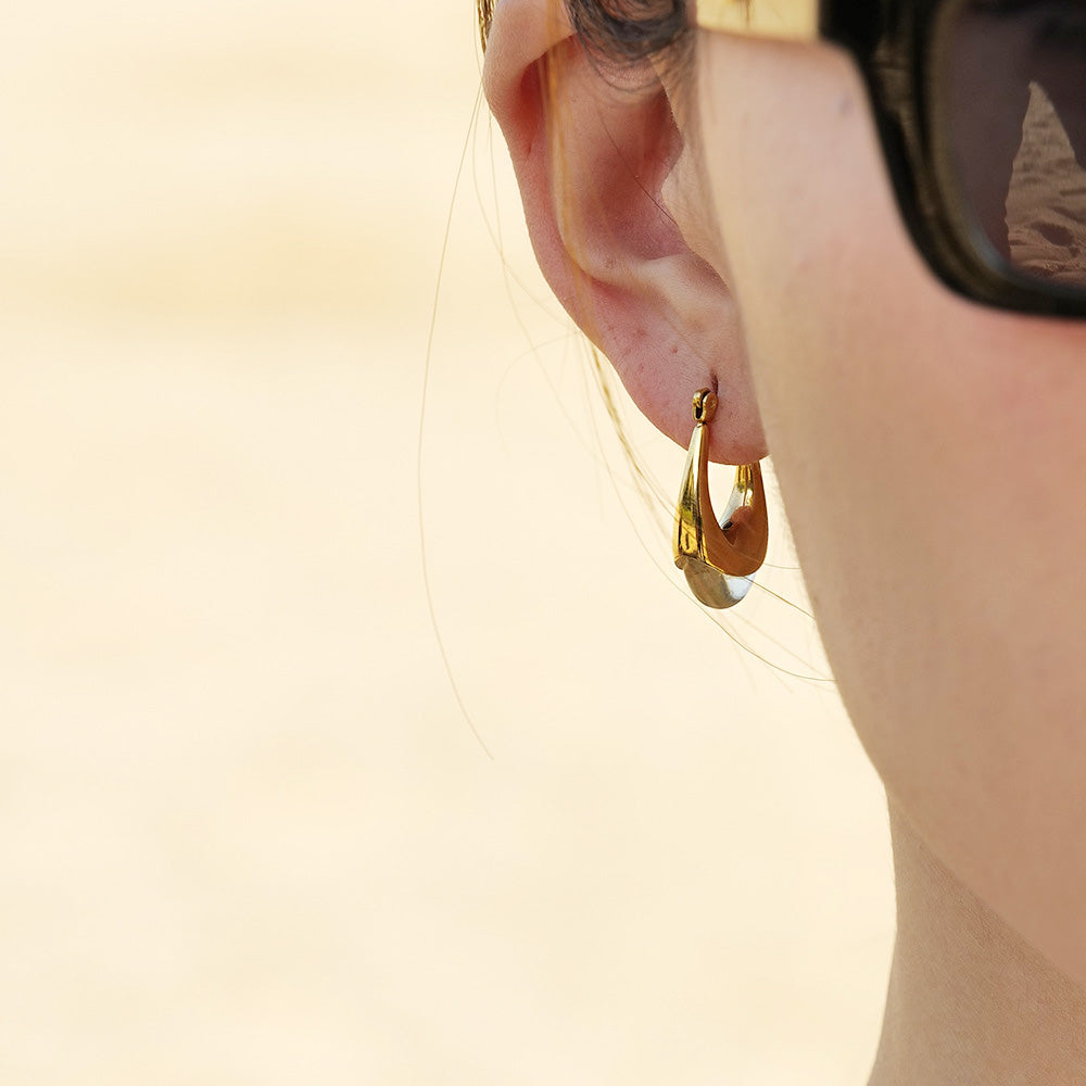 A model showcasing the elegant gold U-shape hoop earring with a clear resin stone.