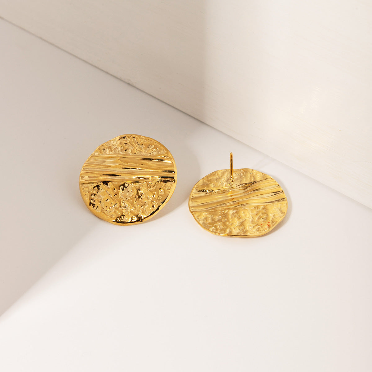Detailed close-up of the hammered texture on the gold stud earrings