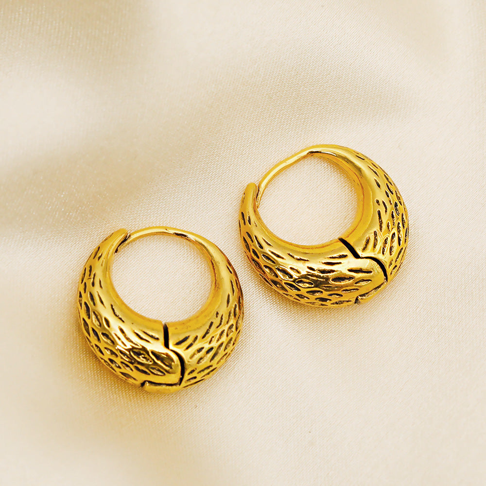 Close-up of the gold textured hoop earring's intricate design