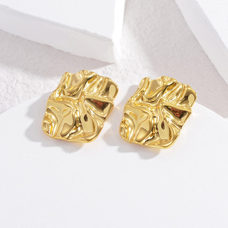 A pair of gold chunky earrings with a unique wavy texture.