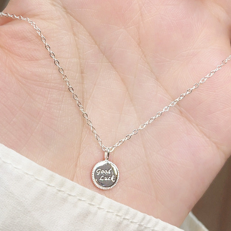 A hand holding the delicate 925 sterling silver good luck coin necklace to show its size.