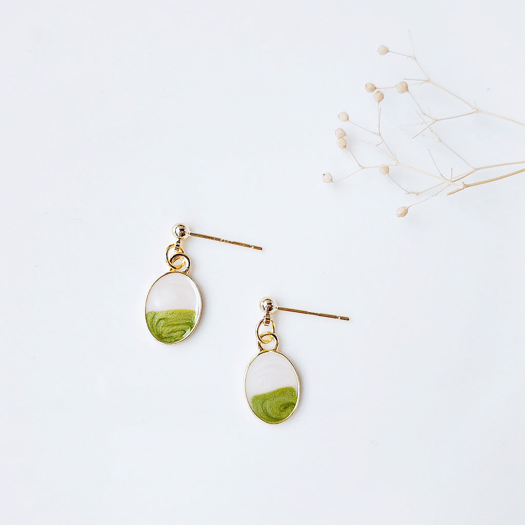 A pair of unique gold-plated oval earrings with green enamel accents.