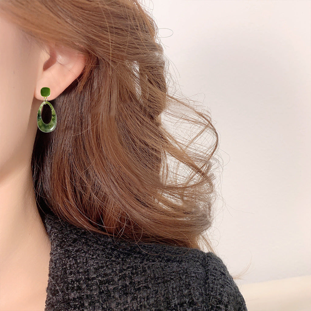 A model wearing the 14k gold plated green resin vintage drop earring.