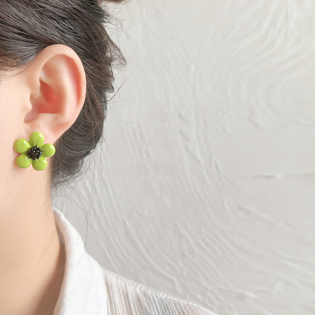 A model wearing the green enamel daisy flower stud earring to showcase its charming look.