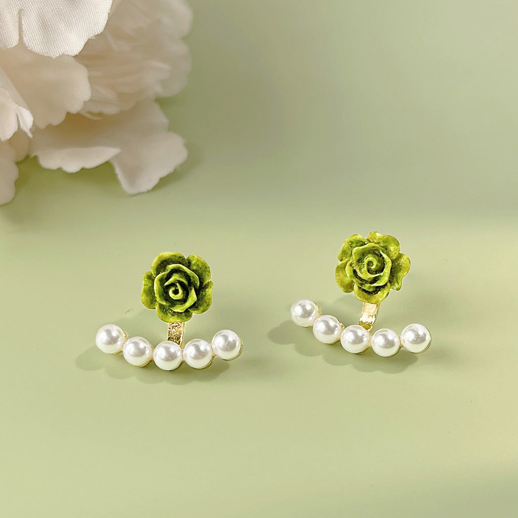 Detailed view of the green resin rose earrings with pearl accents