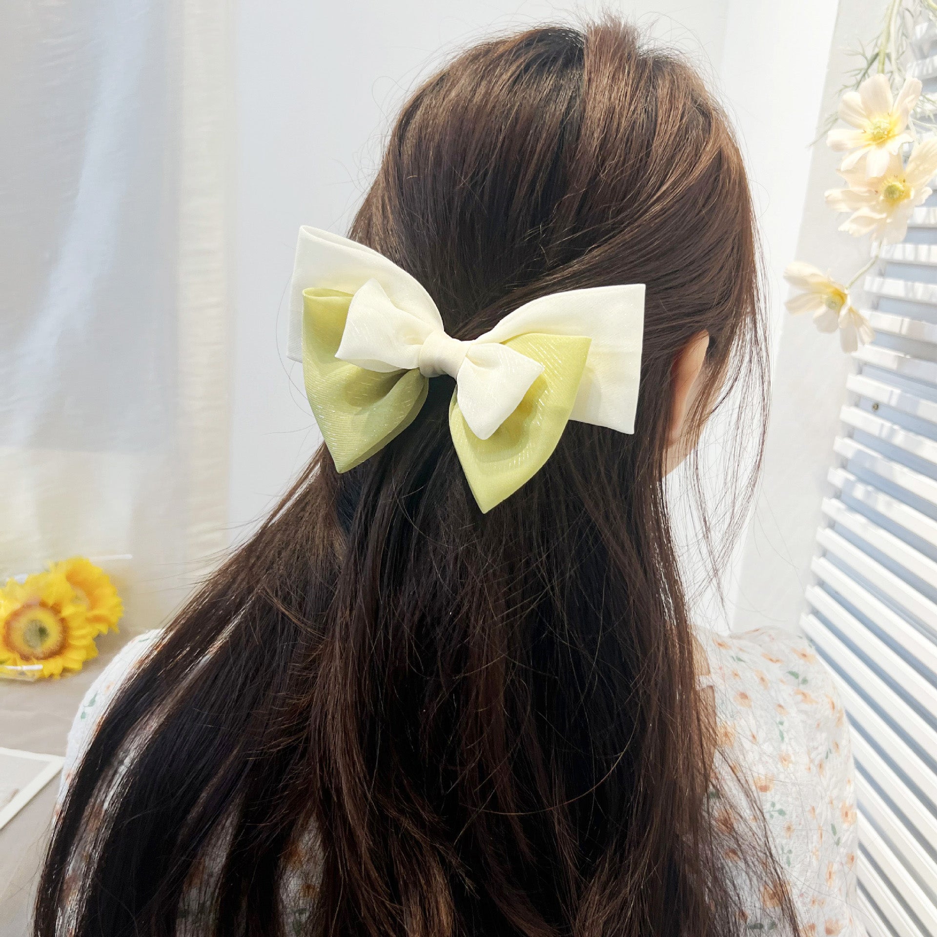 A model wearing a large double-color ribbon bow hair clip