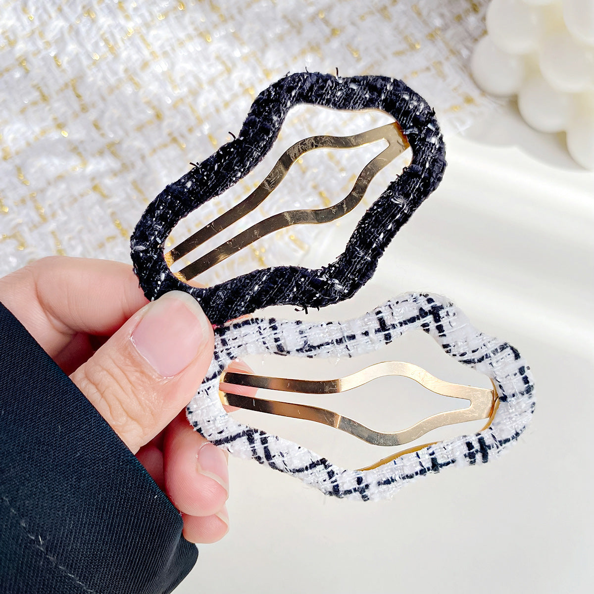 A pair of fabric-covered snap hair clips in black and white