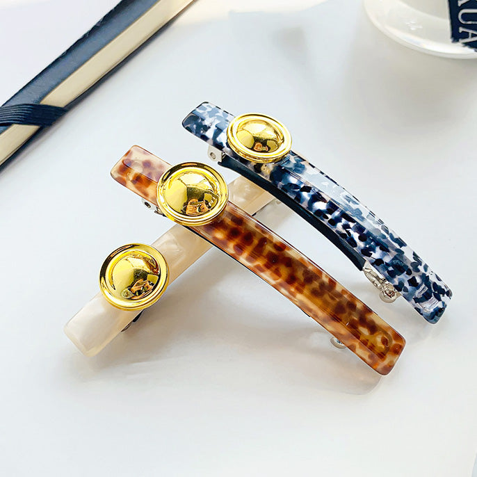 Close-up of acetate hair clips with gold details