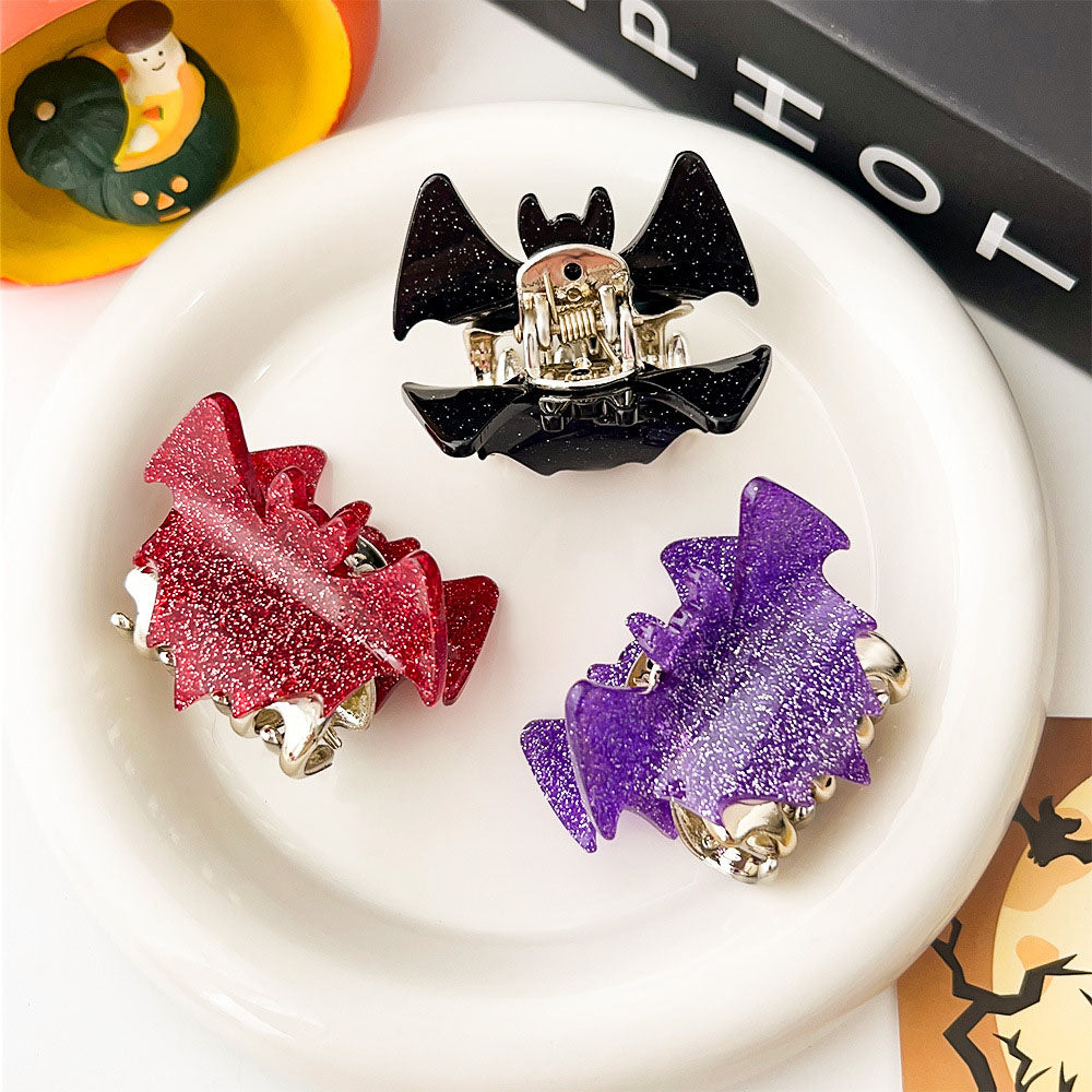 Three bat-shaped hair clips in black, red, and purple with glitter finish