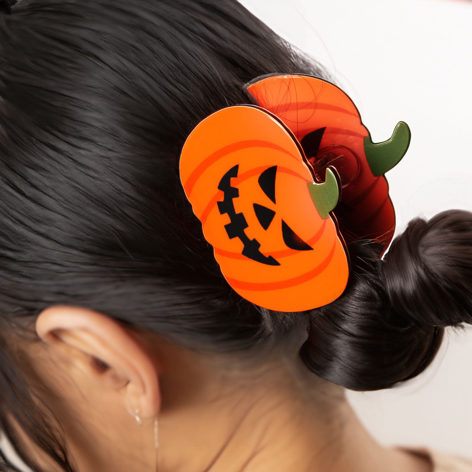 A woman's hand holding a single pumpkin hair clip to show its size and design