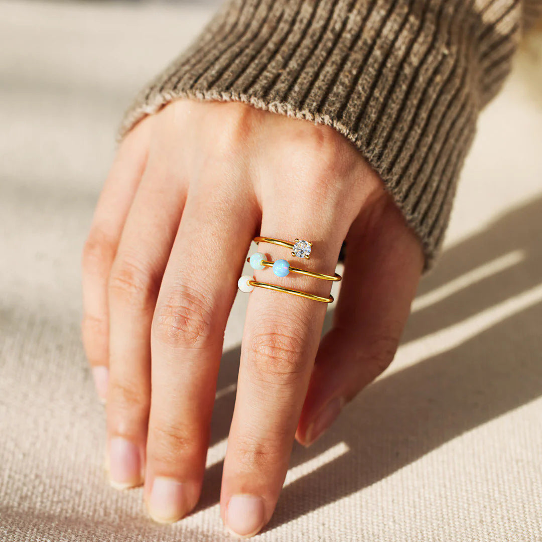 A model's hand wearing the Starlit Ocean ring set in a luxurious gold finish