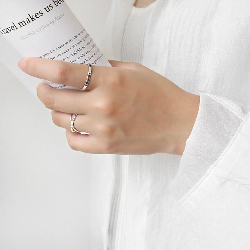 A close-up of the sterling silver crossover ring being worn, showing the adjustable double-band detail.