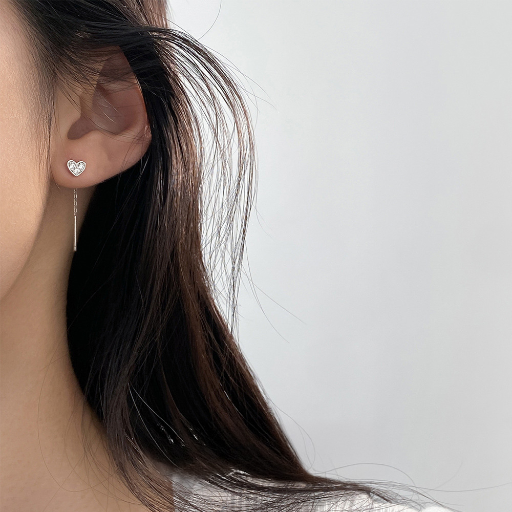 A woman wearing a 925 silver heart earring to showcase its minimalist style.