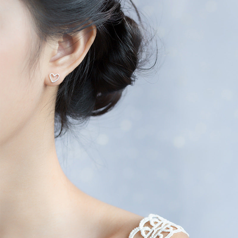 Model showcasing the delicate 925 sterling silver hollow heart stud earring