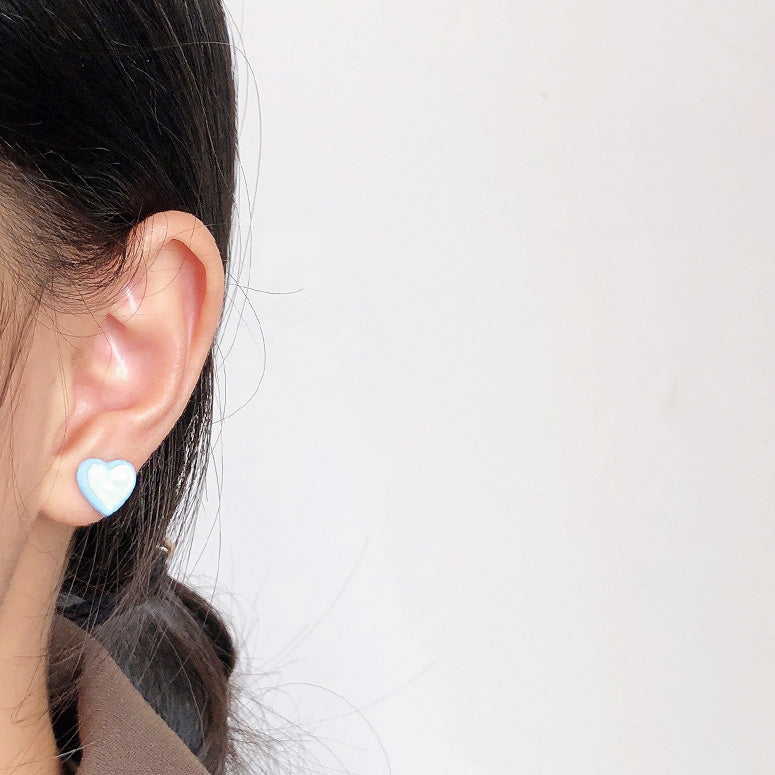 A model wearing a blue enamel heart stud earring to show its size and style.