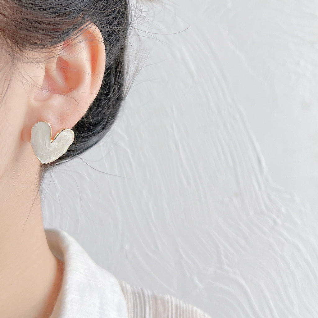 Model showcasing the white enamel heart stud earring