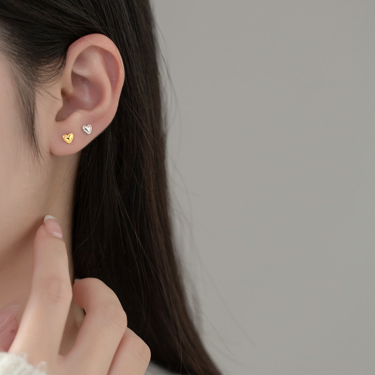 Model wearing the silver heart stud earring to showcase its size and fit