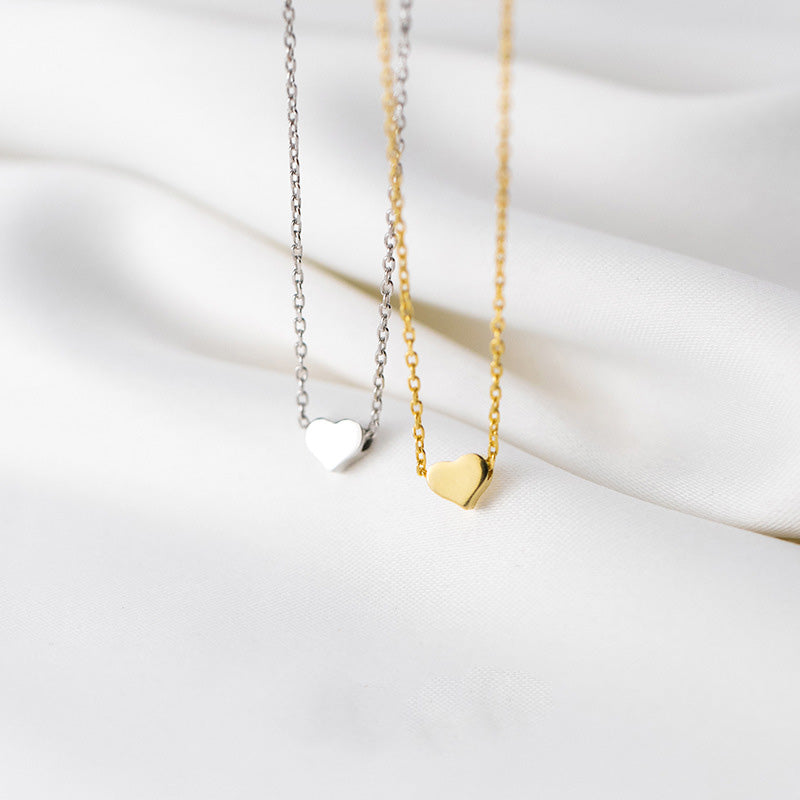 A pair of 925 sterling silver heart necklaces, one in silver and one in gold, on a white background