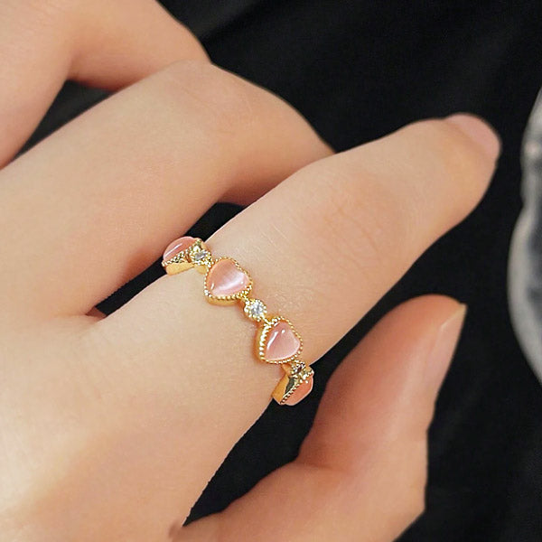 A model wearing the 14k gold plated pink opal heart ring to show its scale and appearance.