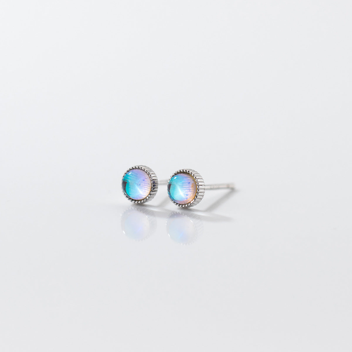 Detailed view of a round moonstone stud earring with intricate silver edging.
