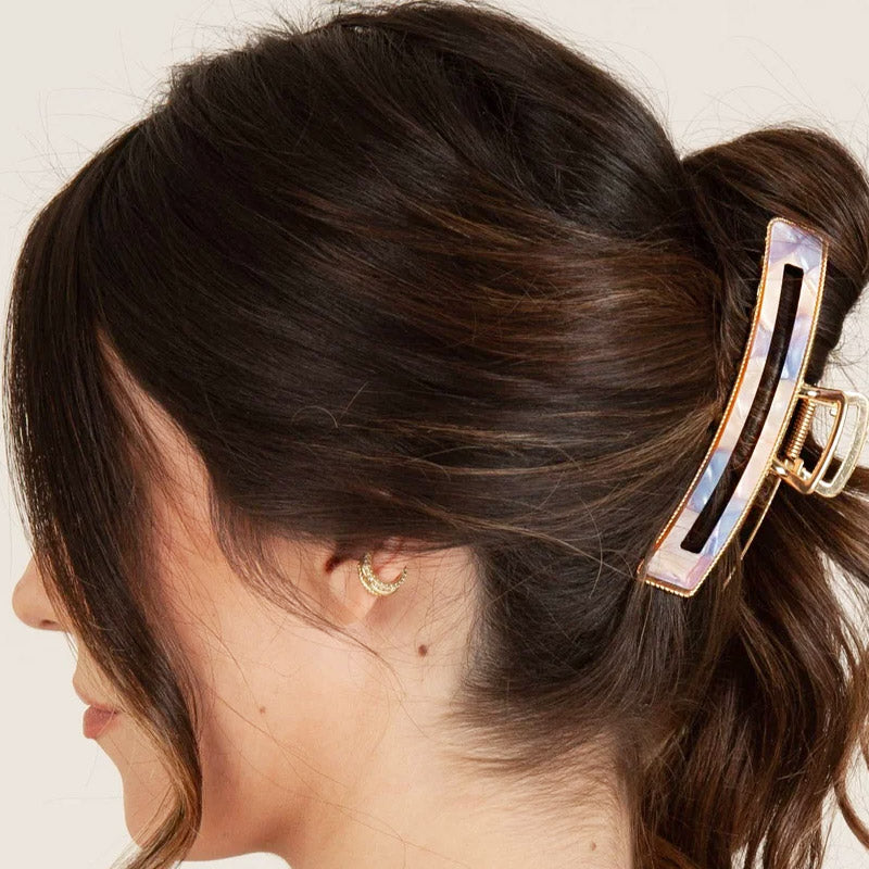 A stylish iridescent hair clip securing a half-up bun hairstyle.