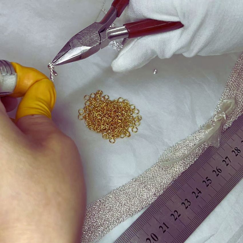A close-up view of a craftsman assembling a fine jewelry chain at JR Fashion Accessories.