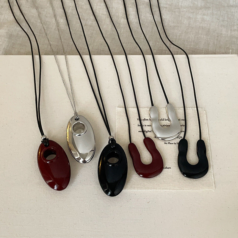 A collection of minimalist cord necklaces with U-shape and oval pendants