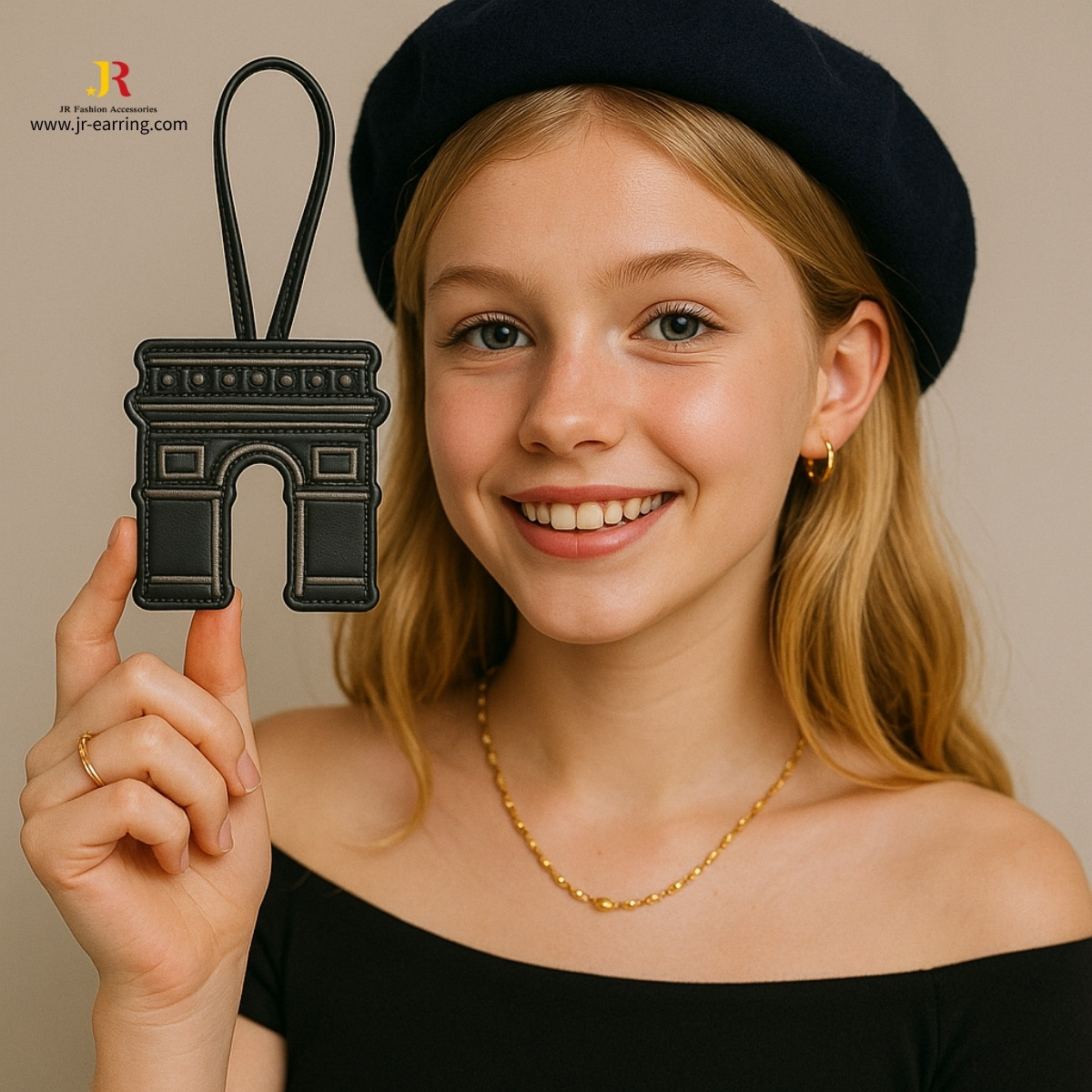 A close-up of a black leather keychain in the shape of the Arc de Triomphe by JR Fashion Accessories.