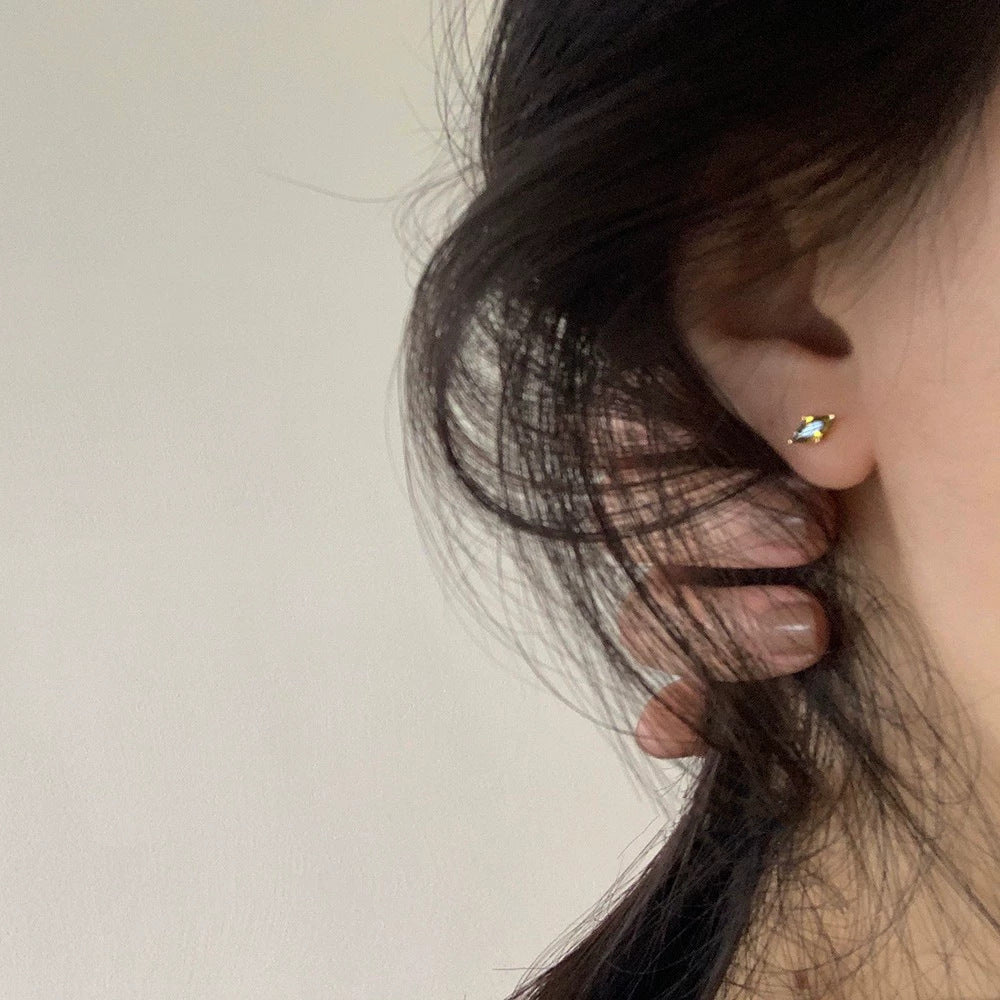 A close-up of the olive green marquise stud earring being worn.