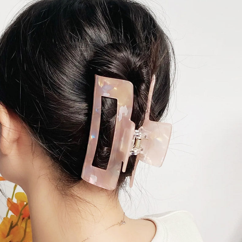 A large pink acetate hair clip holding a woman's bun securely.