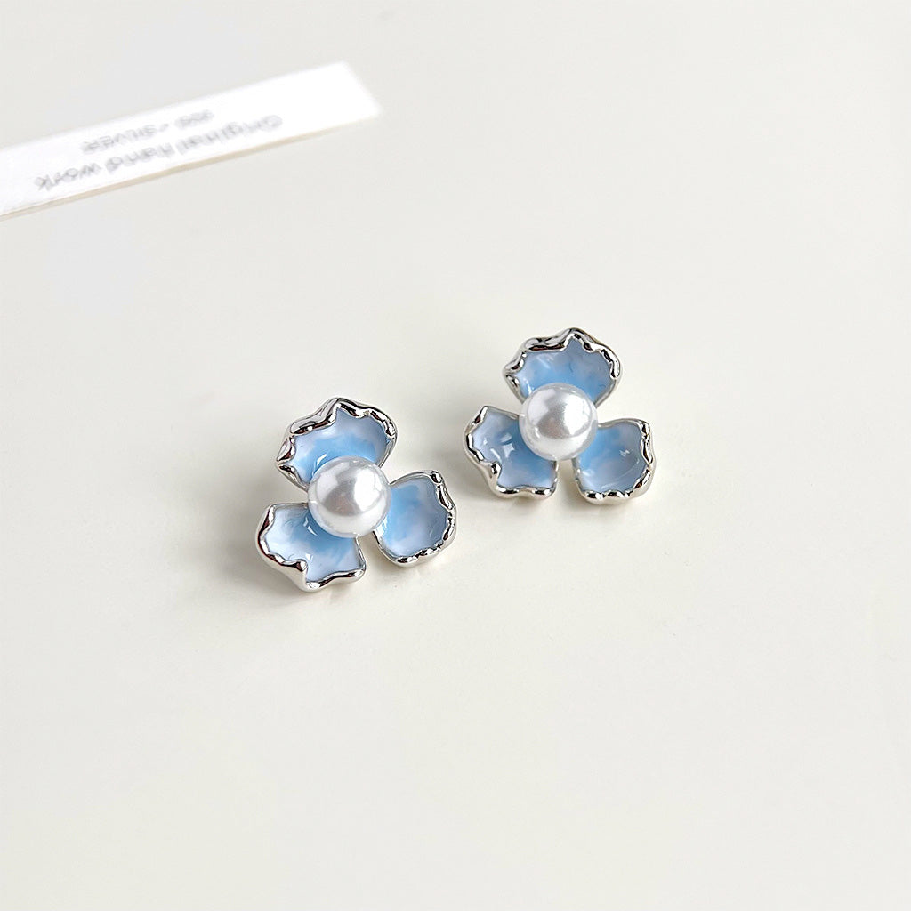 Detailed view of the gradient blue enamel and pearl on the iris flower earrings