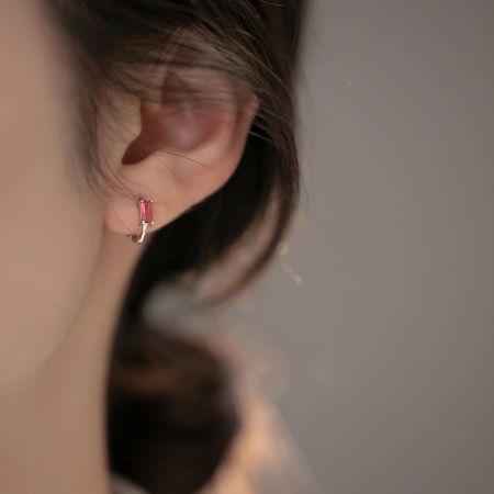 Close-up van een model met de roze zirkon sterling zilveren huggie oorbel.