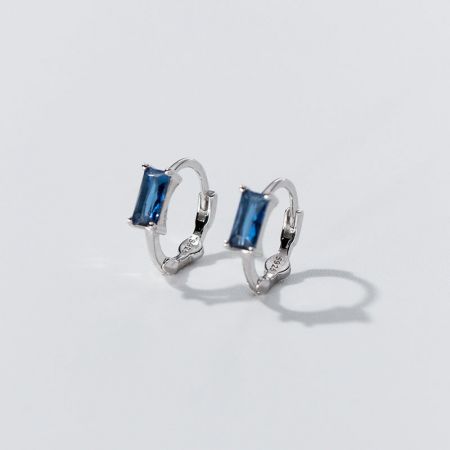 Een paar elegante zilveren creolen met levendige blauwe edelstenen.
