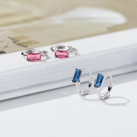 Een paar sterling zilveren creolen met blauwe en roze rechthoekige edelstenen.