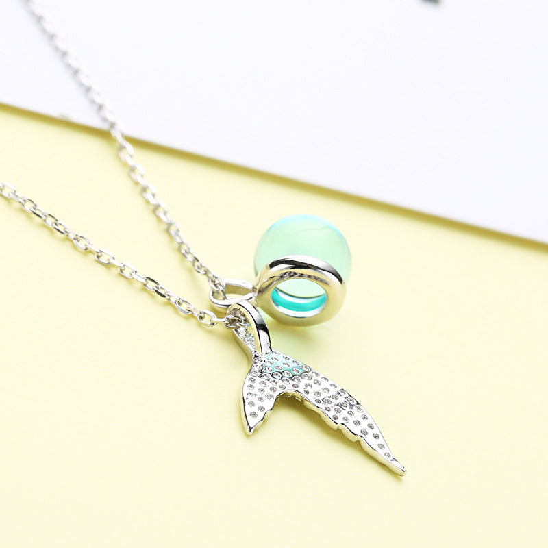 Detailed view of the sterling silver whale tail pendant with a mint green moonstone