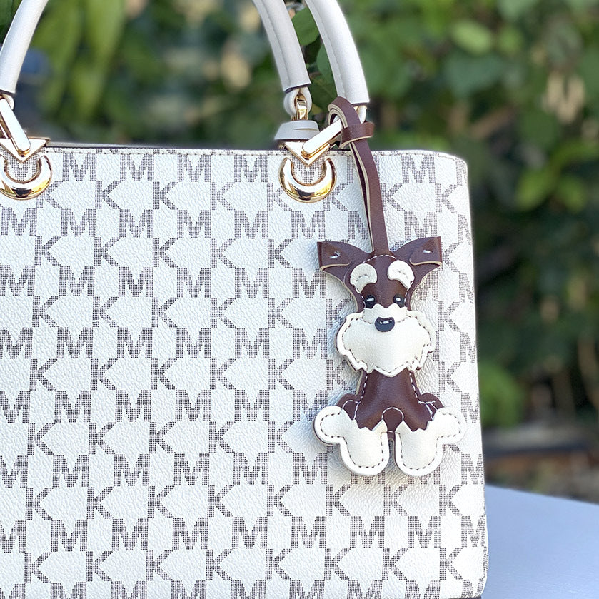 A stylish Michael Kors handbag adorned with the Schnauzer leather dog keychain, showing its application as a fashion accessory.