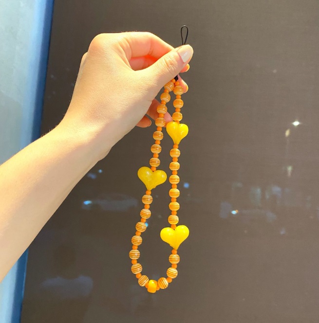 Detailed view of the orange beaded phone strap with heart decorations