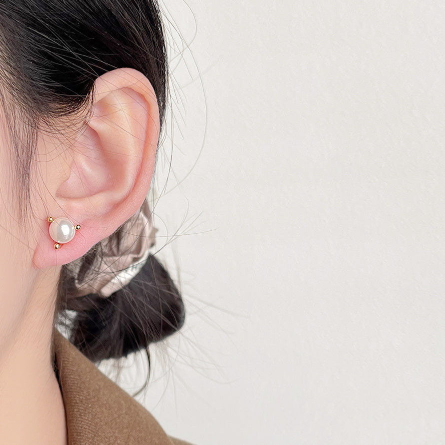 A woman wearing a 14k gold plated simple pearl stud earring