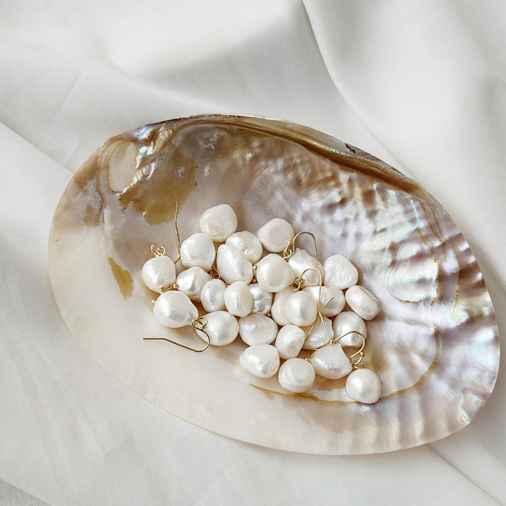Baroque pearl earrings elegantly displayed in a seashell