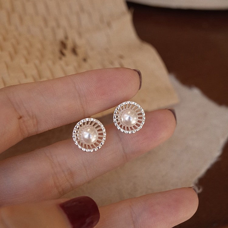Detailed view of the pearl stud earrings, showing the circular design and sparkling clear stone accents.