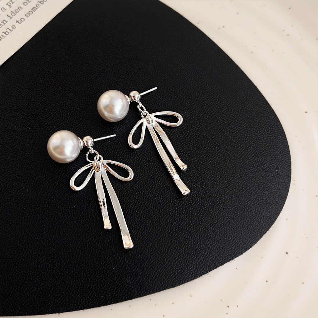 Detailed view of the pearl earrings with silver bow charms