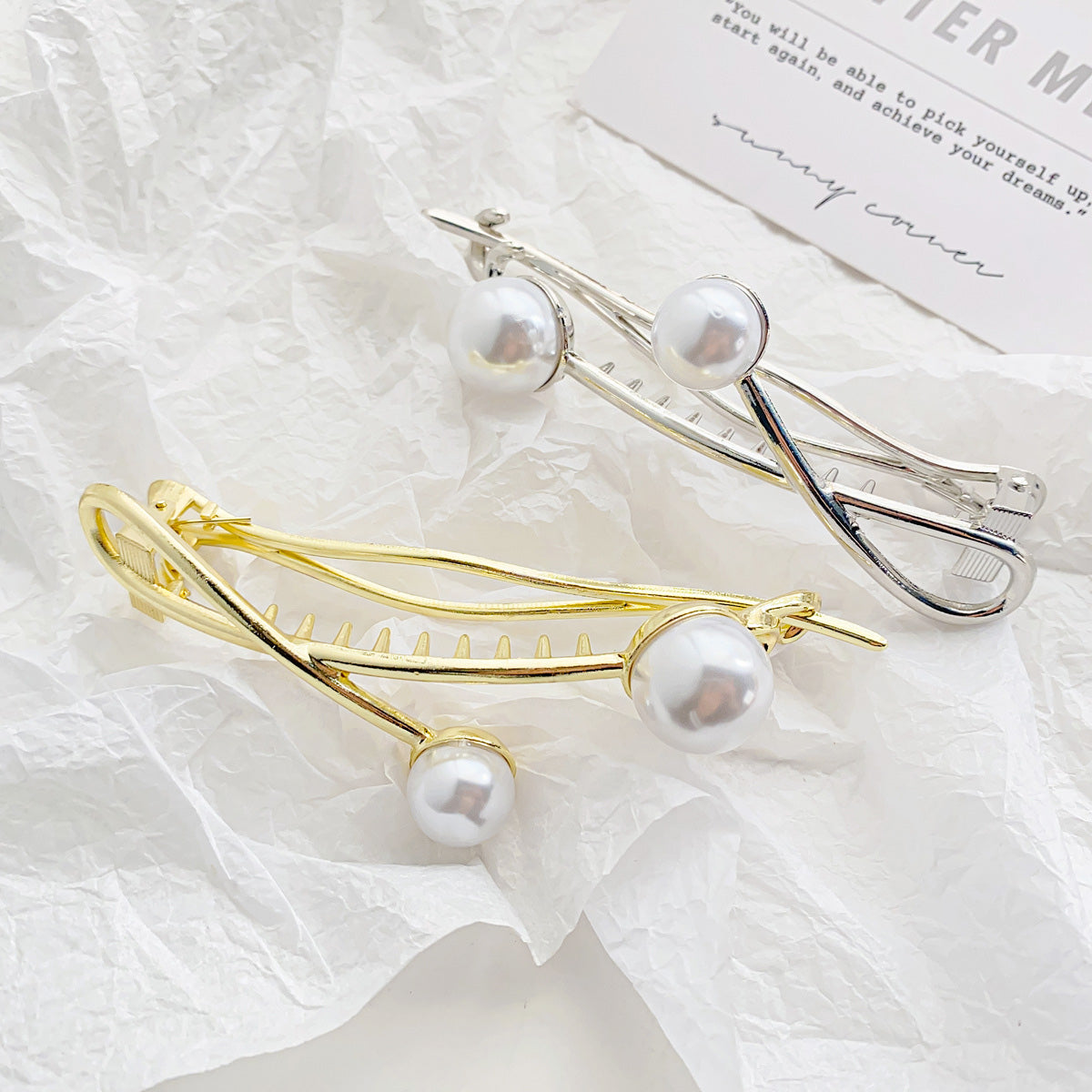 A collection of twisted double pearl hair clips in gold, silver, and black finishes.