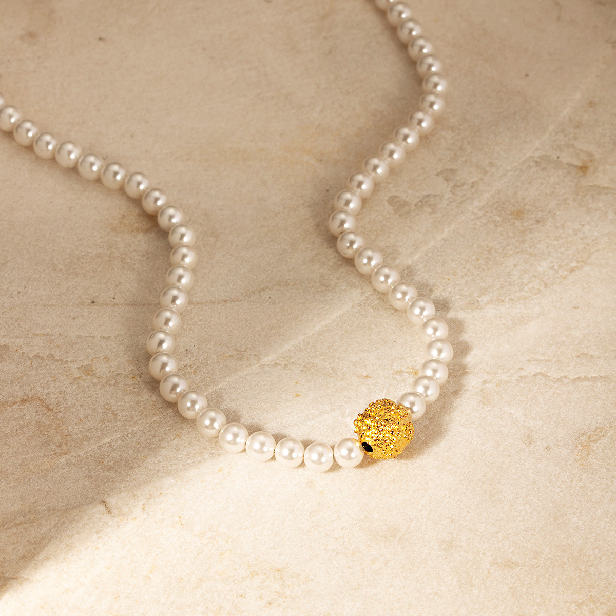 Detailed view of the gold pendant on the pearl necklace