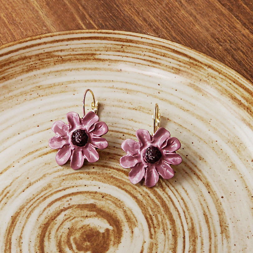 Enamel flower earrings displayed on a decorative plate to show design details.