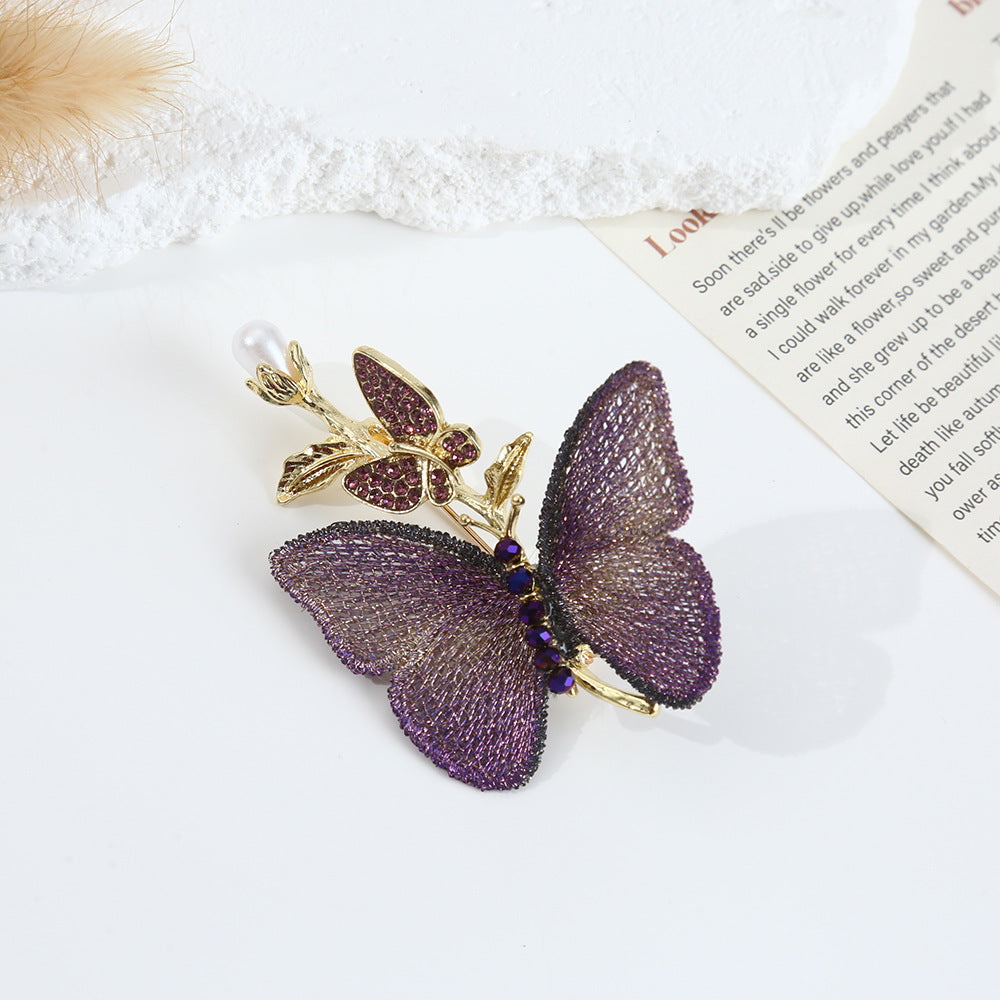 Detailed close-up of the purple embroidered butterfly brooch
