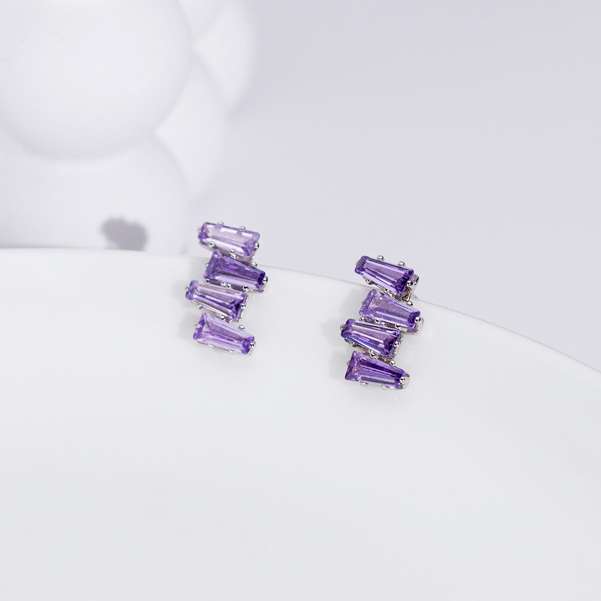 Detailed close-up of the purple crystal jagged baguette stud earrings