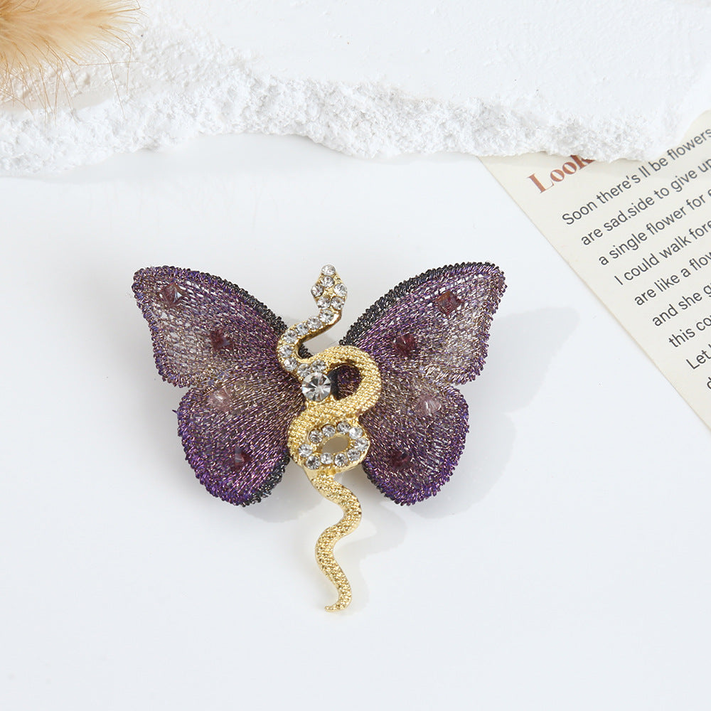 Detailed view of the purple butterfly brooch with gold snake design