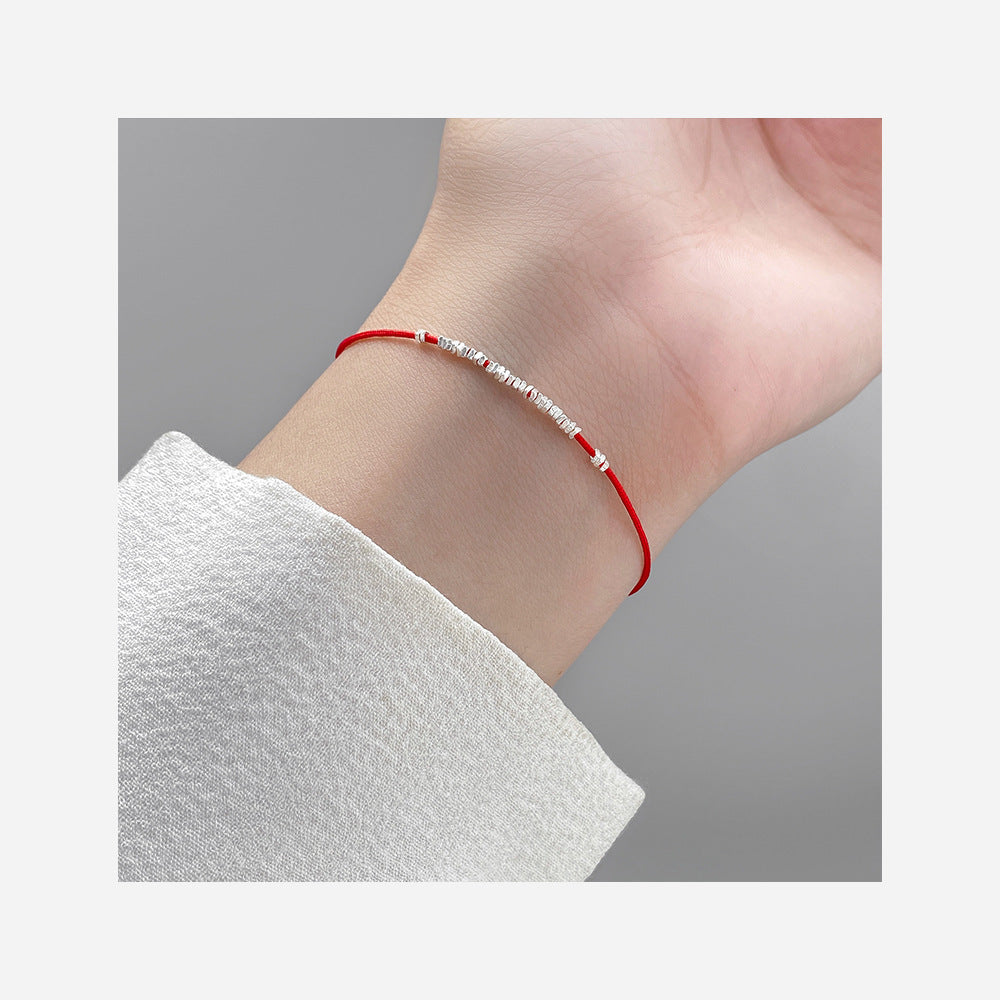 A close-up view of the red cord 925 silver bracelet worn on a wrist, showcasing its minimalist design.
