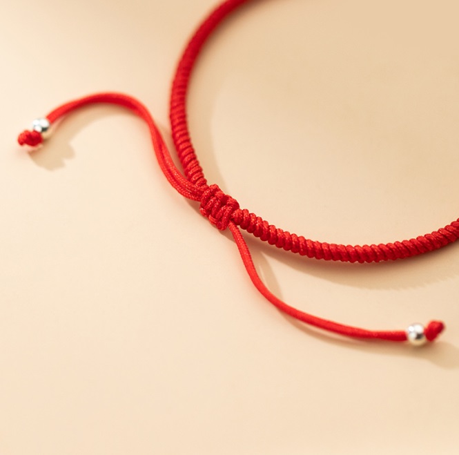 Detailed view of the red rope bracelet with silver beads